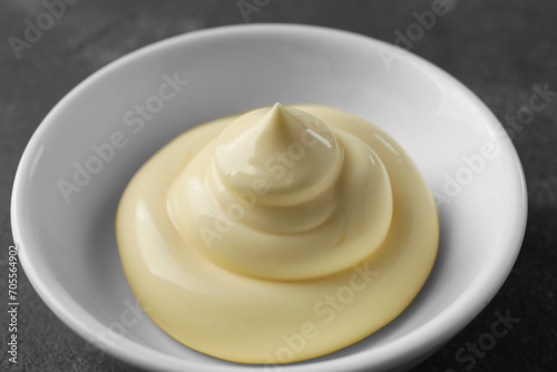 Fresh mayonnaise sauce in bowl on grey table, closeup
