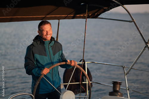 Mature man standing near the steering whell on the yacht © zinkevych