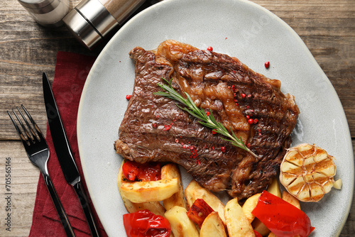 Delicious grilled beef steak and vegetables served on wooden table, top view
