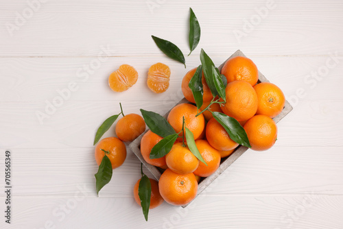 Delicious tangerines with leaves on white wooden table, flat lay