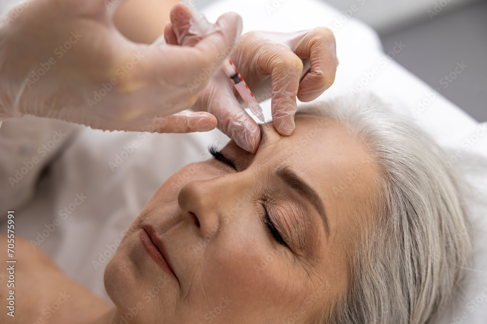 Beautician injecting filler into forehead of a female patient Beautician injecting filler into forehead of a female patient