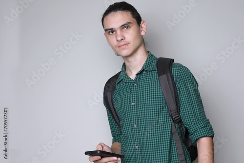 Student handsome long-haired guy with backpack and phone, free copy space