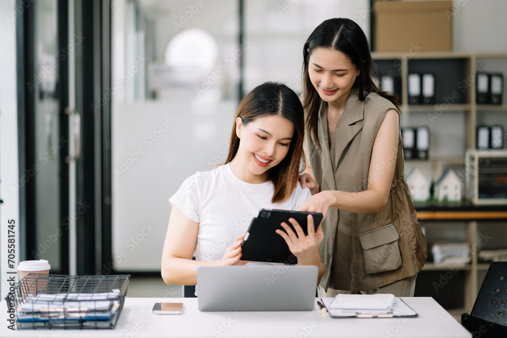 Two Asian businesswoman discuss investment project working and planning strategy with tablet laptop computer Two Asian businesswoman discuss investment project working and planning strategy with tablet laptop computer