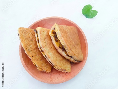 pieces of martabak filled with chocolate sprinkles on a wooden plate on a white background. martabak, traditional Indonesian sweet snack. soft bread filled with chocolate, for tea time or celebrition photo