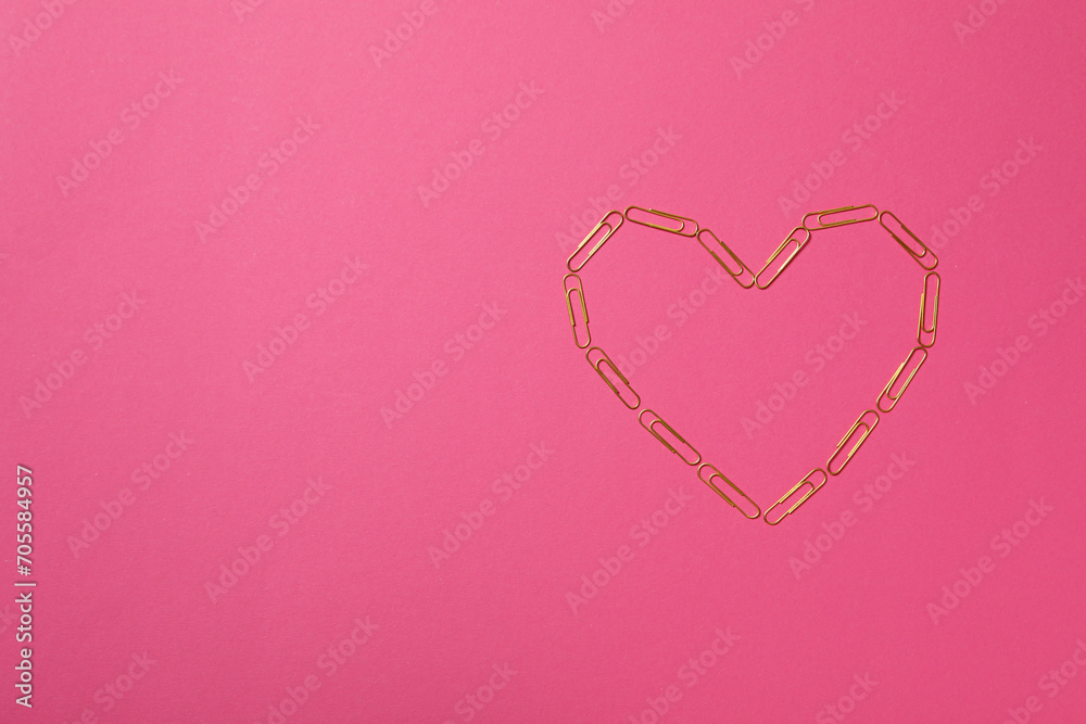 Heart from paper clips, on a red background.