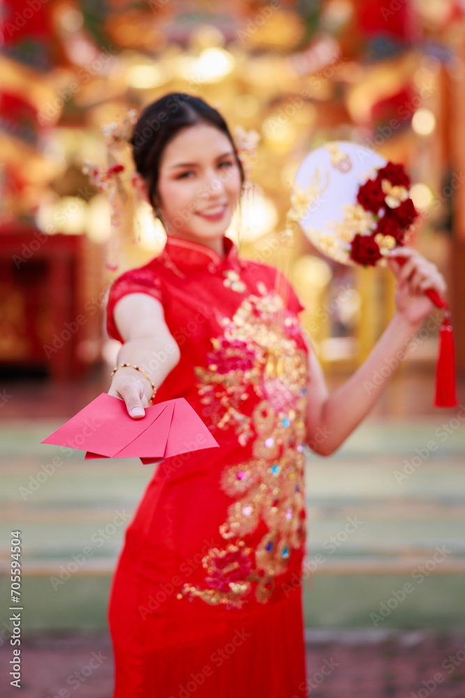 Portrait of young asian woman with traditional Chinese red drese, standing smilling holding angpao envelope inside the temple, Chinese new year , concept Portrait of young asian woman with traditional Chinese red drese, standing smilling holding angpao envelope inside the temple, Chinese new year , concept