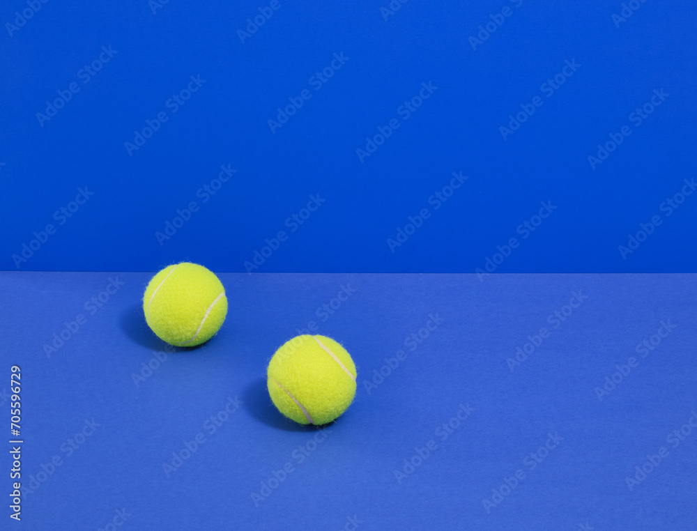 Two bright yellow tennis balls on a blue background. Copy space for text. Set of various sport supplies.