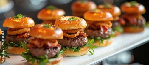 Miniature grilled beef burgers, onion rings, and bacon served as shared appetizers.