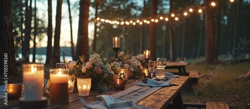 Outdoor wedding reception in pine forest. Boho-style decorated dining area with candles, flowers, and lights. Eco-friendly floral arrangements.