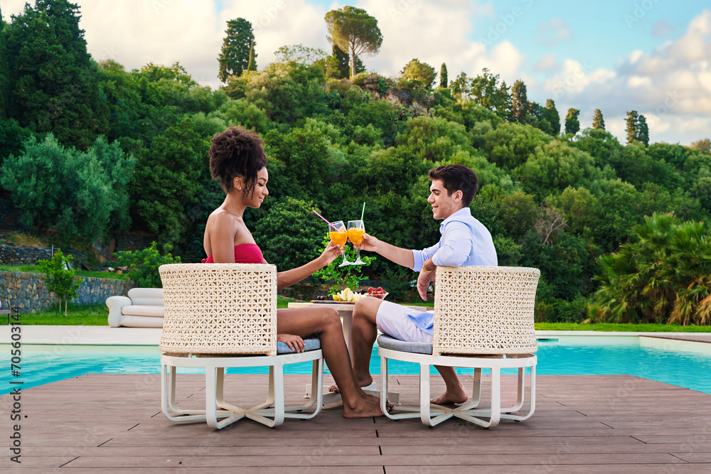Fototapeta premium Couple Toasting Drinks by the Pool