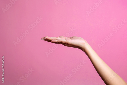 Female hand presenting and holding empty space for product placement or ads over pink background