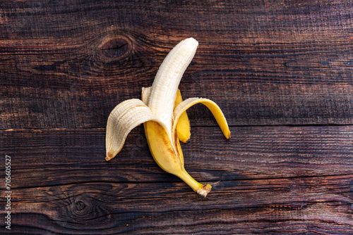 whole fresh tasty Half Peeled banana without skin on brown wooden background, Composition of fresh fruits, top view