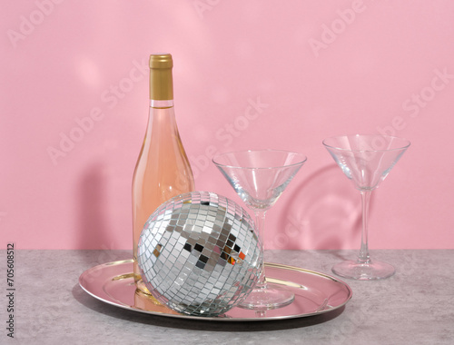 Concept disco and alcohol party. Bottle of wine on a tray, dico ball and glasses. photo