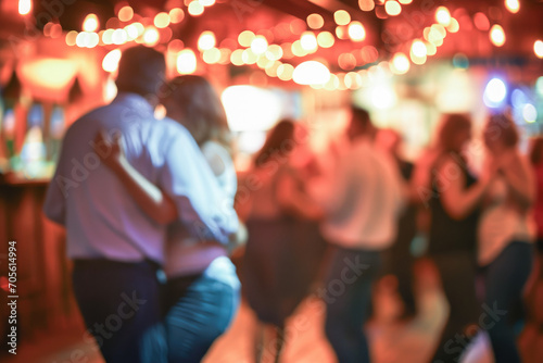 Blurred image of people dancing at a lively party with colorful lights in the background.