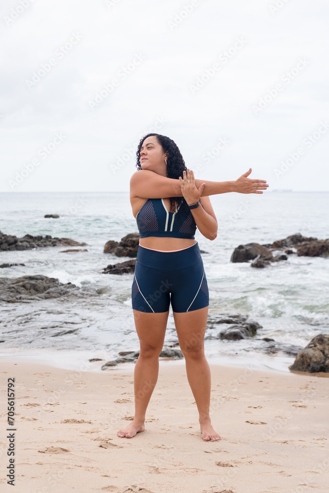 Beautiful young woman in gym clothes doing stretches on the beach sand. Beautiful young woman in gym clothes doing stretches on the beach sand.