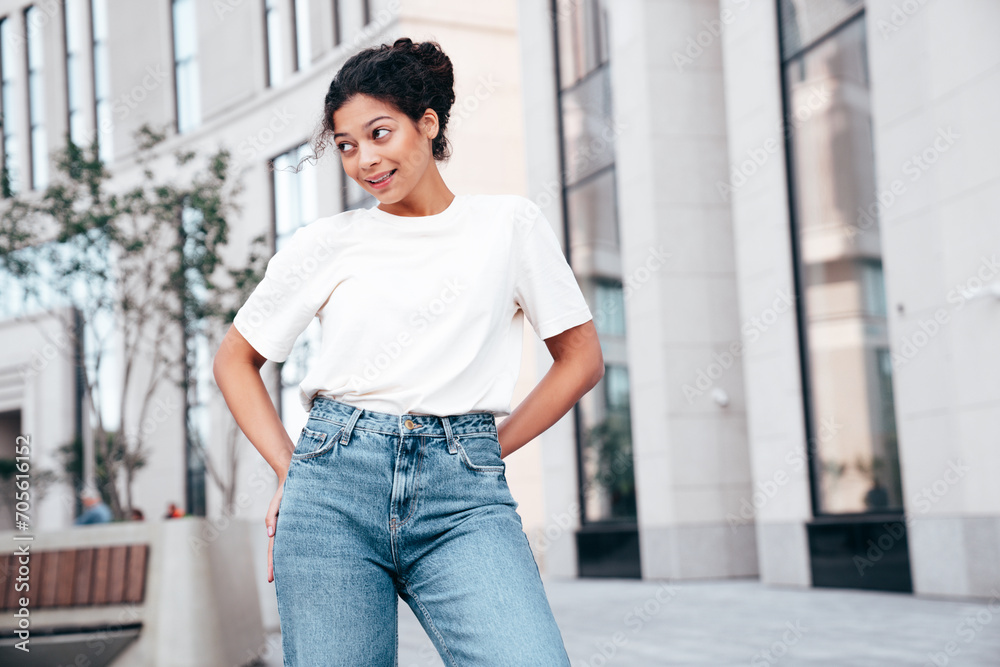 Young beautiful smiling hipster woman in trendy summer white t-shirt and jeans clothes. Carefree woman, posing in the street at sunny day. Positive model outdoors. Cheerful and happy. Young beautiful smiling hipster woman in trendy summer white t-shirt and jeans clothes. Carefree woman, posing in the street at sunny day. Positive model outdoors. Cheerful and happy.