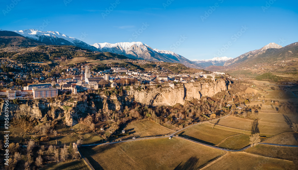 Winter panoramic view of Embrun and its famous cliff-top plateau with harvested fields in Durance Valley in the Hautes-Alpes. French Alps, France