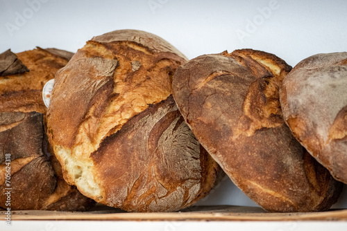 Close-up image of rustic round loaves of artisan bread with a golden-brown, crusty exterior, displayed on a wooden shelf in Altamura, Bari, Puglia region, Italy