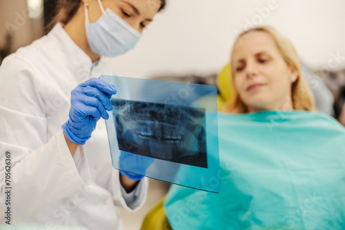 Selective focus on dentist s hand holding x-ray and showing to a woman at dentist office.