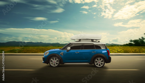 Blue SUV car with luggage box mounted on the roof. Driving on the road with motion effect. Roof box for car extra capacity in action.
