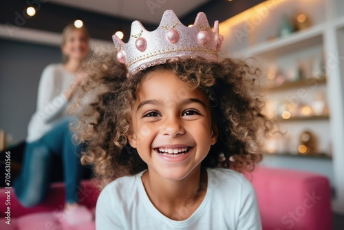 Cute little black girl wearing a toy crown is happy and smiling. Children's birthday. photo