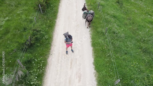 Man Hiking With A Donkey on a Countryside Path Film Himself With a Drone photo