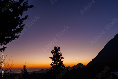 Silhouette of a mountain and a tree against the background of dawn.  Antalya. Turkey.