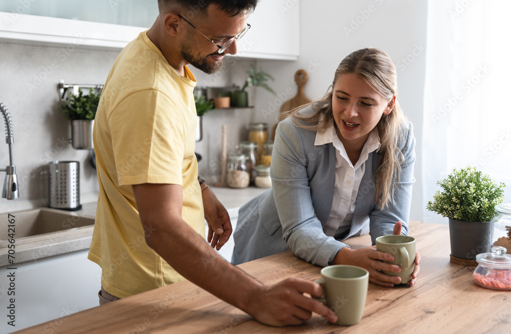 Business colleagues talk during lunch break in office kitchen. Woman communicates with workmate hold coffee cups enjoy conversation, discuss work or personal. Good relations at work concept