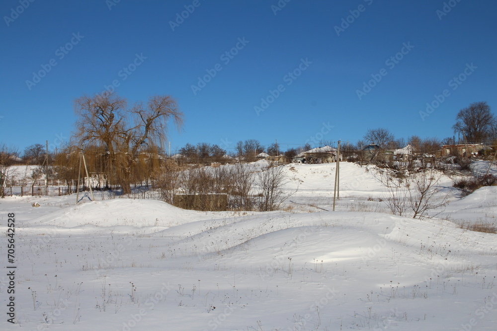 A snowy field with trees and buildings with Salton Sea in the background