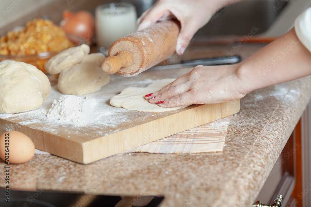 woman hand holds a rolling pin over rolled out dough....