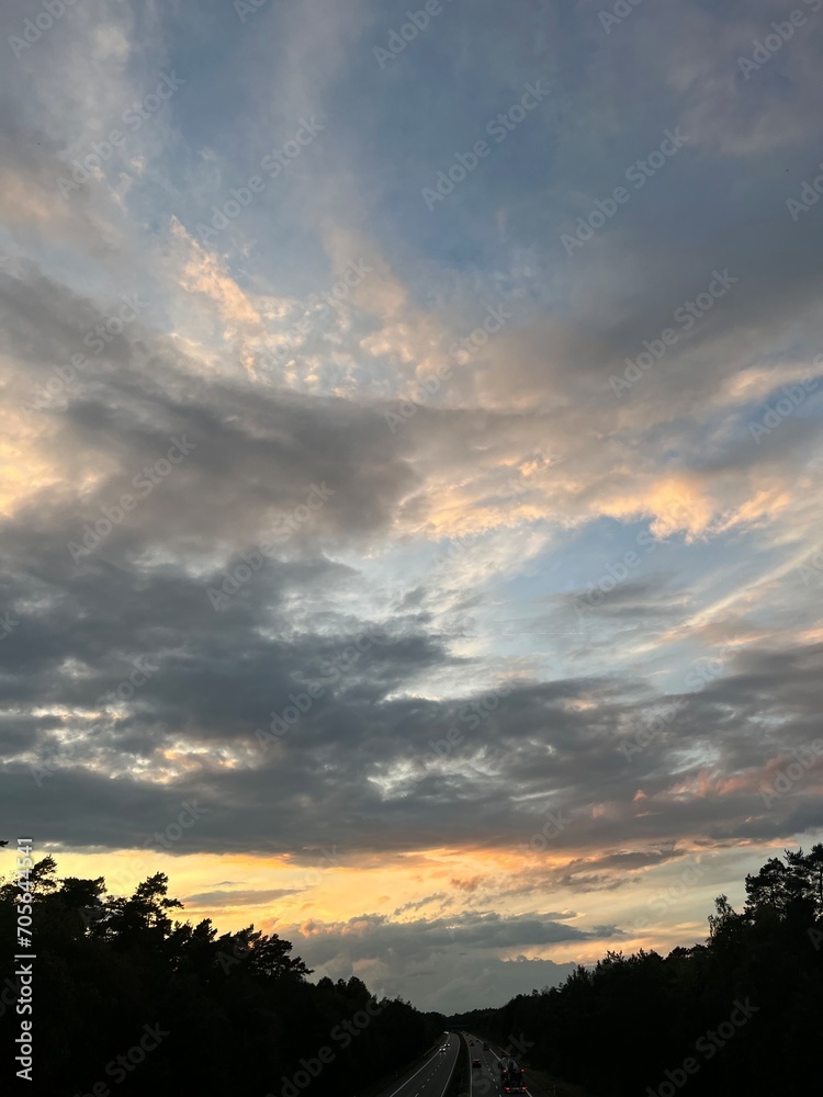 Fototapeta premium highway in the countryside, dramatic clouds at the sunset sky