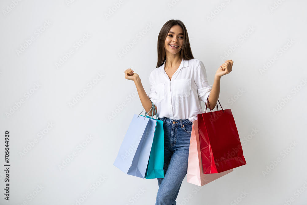 A young woman holds numerous shopping bags on a white background. A young woman holds numerous shopping bags on a white background.