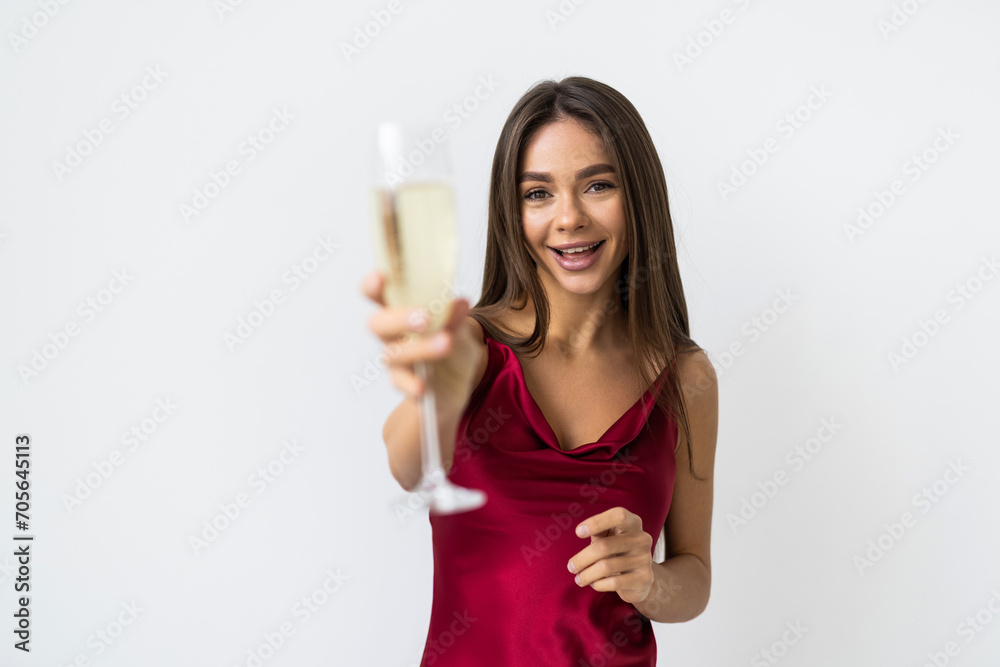Portrait of a cheerful young woman dressed in red dress holding glass of champagne isolated over white background Portrait of a cheerful young woman dressed in red dress holding glass of champagne isolated over white background