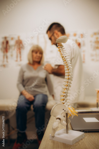 A happy senior woman lies on an examination couch while a chiropractor, osteopath or physiotherapist examines her back. Treatment of osteoporosis, physiotherapy, concept of physical therapy. photo