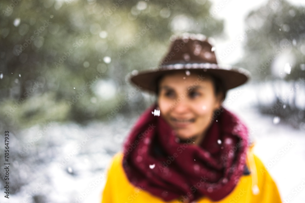 Female traveler with yellow rain coat and cowboy hat enjoying snowy day, smiling