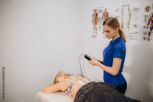 An elderly female patient is using electrical stimulation therapy TENS on her back photo