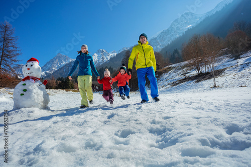 Family's winter joy on sunny snowy field over French mountains