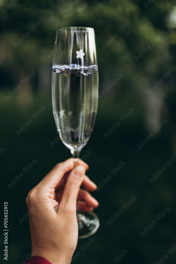 on a fresh green background, a girl's hand holds a glass containing a drink with small beautiful details in the form of flowers