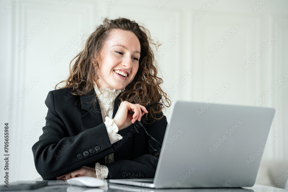 Joyful businesswoman laughing during a video call on her laptop, enjoying a light-hearted moment at work. Joyful businesswoman laughing during a video call on her laptop, enjoying a light-hearted moment at work.