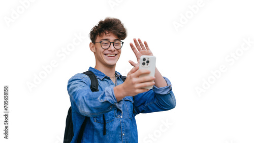Obraz na plátne Cheerful teen boy in glasses, jeans shirt makes video call by phone waving hand saying hello, toothy smiles standing against transparent background
