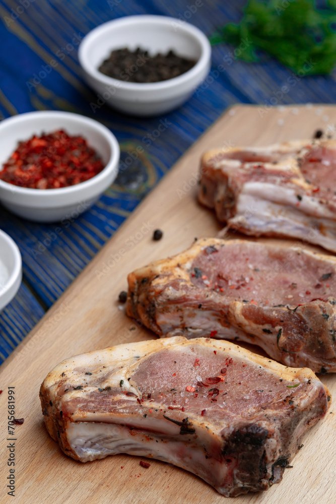 Raw pork ribs with spices and herbs on cutting board on wooden background