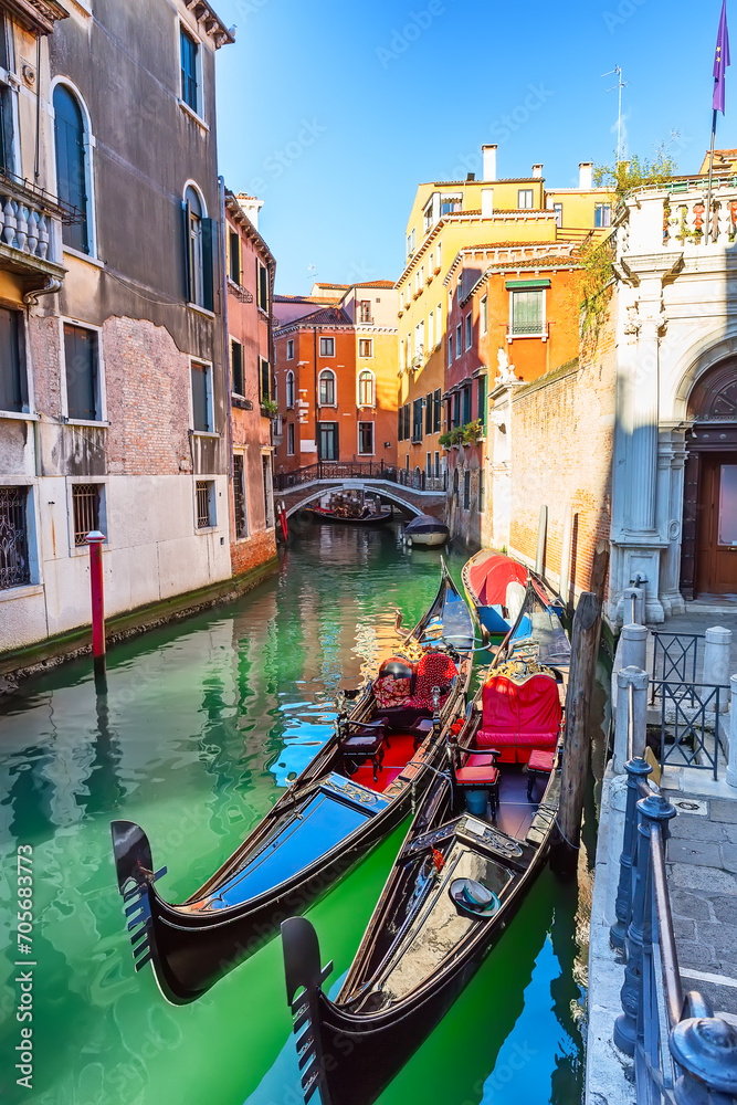 Traditional gondolas and bridge on narrow canal in Venice, Italy.