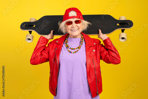 Smiling senior modern urban caucasian woman with skateboard looking at camera