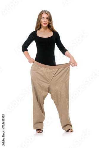 Obraz na plátne Side view of young woman showing her clothes before and after losing weight, Stu