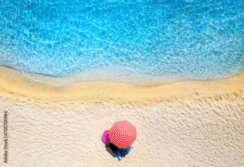 Fototapeta Naklejka Na Ścianę i Meble -  Aerial view of blue sea, empty sandy beach and umbrella at sunset in summer. Tropical landscape with clear turquoise water. Top view from drone of seaside. Lefkada island, Greece. Travel background