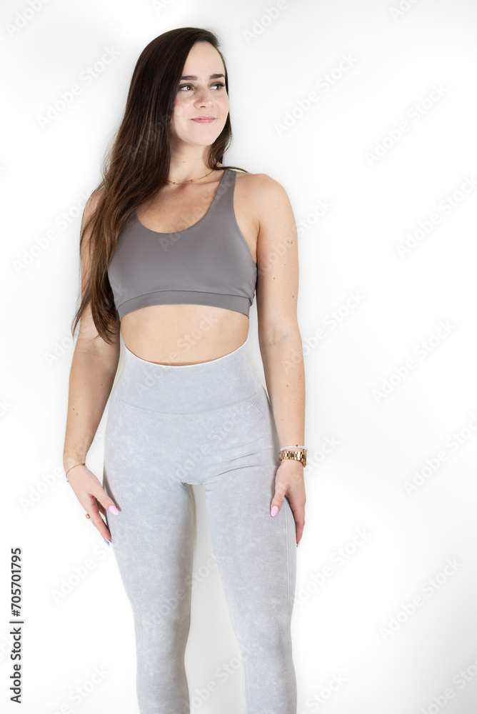 a woman is wearing grey and posing for the camera, with her hands on her a woman is wearing grey and posing for the camera, with her hands on her