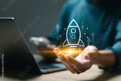 Startup business concept, Businessman use laptop with virtual screen of rocket icon and up arrow for fast start up business. Strategic planning and business success. photo
