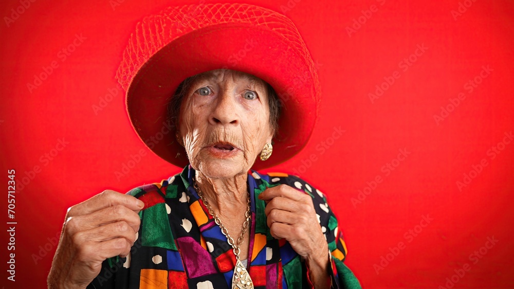 Excited happy fisheye portrait of funny elderly woman with red hat and no teeth isolated on red background. Excited happy fisheye portrait of funny elderly woman with red hat and no teeth isolated on red background.