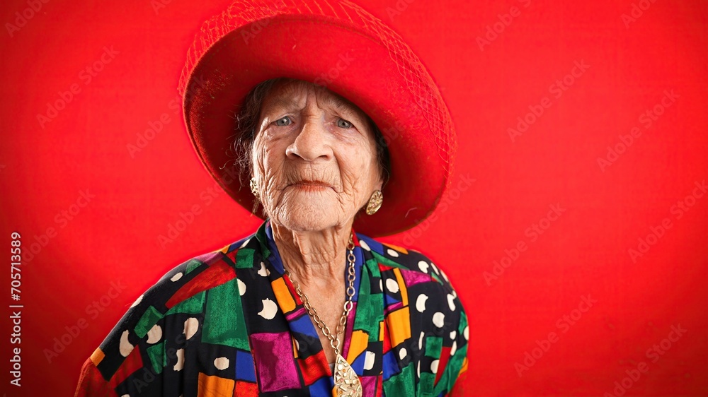 Unhappy displeased fisheye portrait caricature of funny elderly woman saying NO with red hat isolated on red background. Unhappy displeased fisheye portrait caricature of funny elderly woman saying NO with red hat isolated on red background.