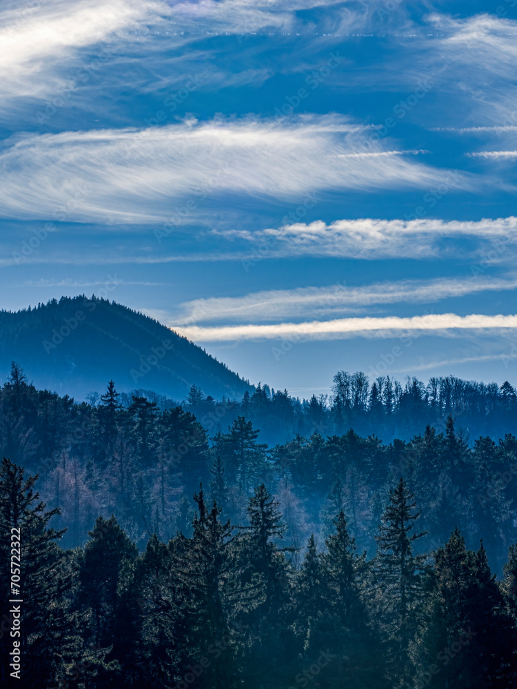 Landscape with mountains and forest on a foggy weather with clear blue sky and a few clouds in the Carpathians Mountains 